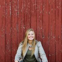 Kendall Keeler  sitting in front of a red barn door